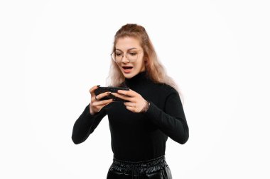 Oh, Tanrım. Elinde telefon olan sevimli genç bir kadın ekranda gördüğü bir şeye şaşırıyor. Teknoloji, gençlik ve iletişim konsepti. Beyaz arkaplan