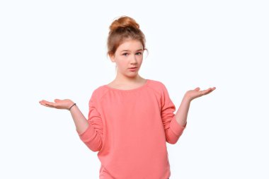 Bilmiyorum, bu ben değilim. Pembe kazaklı kafası karışmış genç bir kız omuz silkiyor. Beyaz arka plan. İnsani duygular, yüz ifadesi kavramı