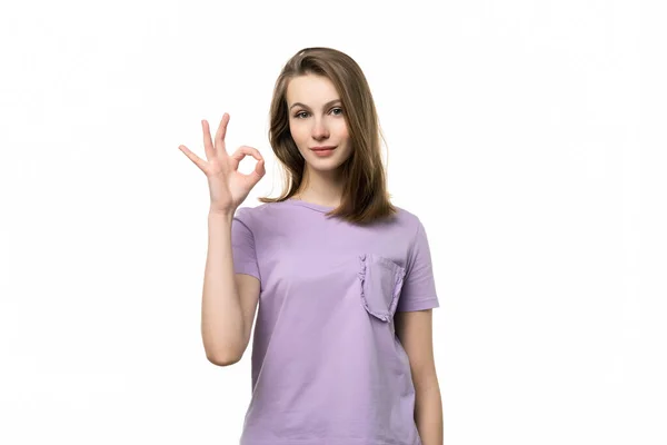 手でOkジェスチャーを示すカジュアルなTシャツの魅力的な女の子の肖像画 人間の感情 ジェスチャーの概念 スタジオショット 白の背景 — ストック写真