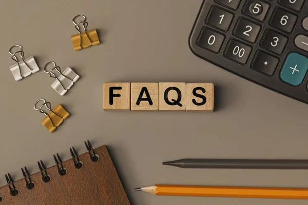 Word - FAQS frequently asked questions - on small wooden blocks on the desk. Conceptual photo. Top view