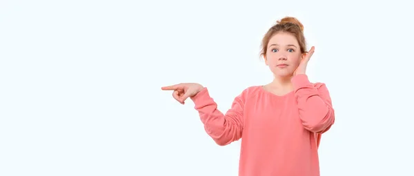 看这里 穿着粉色休闲装的年轻姑娘吃惊极了 她把手指放在一边 看着文案空间 站在白色工作室的背景上 — 图库照片
