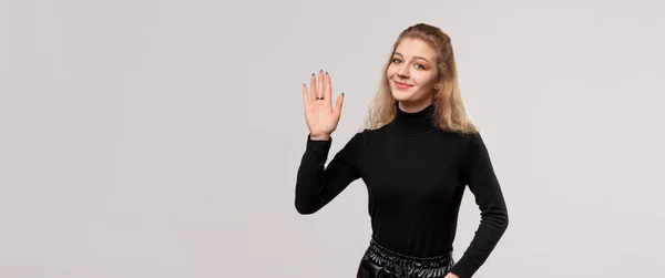 フレンドリーなブロンドの女の子が挨拶をしています 幸せな表情で手で敬礼 5本の指を示します 優しい歓迎ジェスチャー — ストック写真