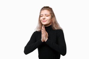 Kapalı gözlerle dua eden genç bir kadın her şeyin yolunda olması için yalvarıyor. Beyaz arka planda duran biri için endişeleniyor. Gerçek insan tepkileri, duyguları ve duyguları