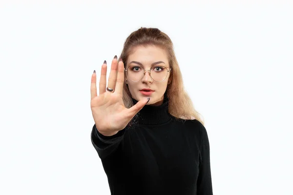Sarışın, uzun kıvırcık saçlı, ciddi, sert, hoşnutsuz ve kızgın bir kadına yaklaşın. Avuç içini açıp durma hareketi yapıyor. Stüdyo çekimi, beyaz arka plan, izole edilmiş, jest konsepti