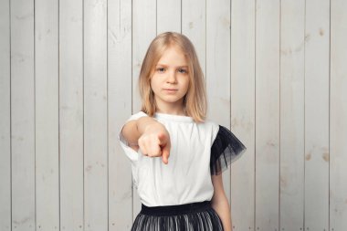 Bu senin hatan. Hoşnutsuz sarışın genç kız sana kızgın ve öfkeli bir şekilde kamerayı işaret ediyor. Stüdyo çekimi, hafif ahşap arka plan