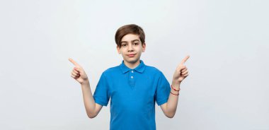 12-14 yaşlarında yakışıklı bir çocuk kameraya bakıyor ve telif hakkı ihlali yapıyor. Önemli bilgilere dikkat edin. Açık gri arkaplanda stüdyo çekimi