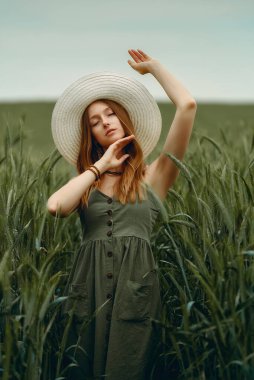 Şapkalı genç bir kadın buğday tarlasında yürüyor, hayattan ve yazdan zevk alıyor. Buğday tarlası. Güneş ışığı altında güzel doğa manzarası. Sağlıklı yaşam tarzı kavramı. Gürültülü görüntü, film tahılı