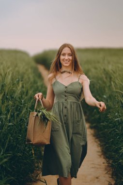 Genç bir kadın buğday tarlasında yürüyor, hayatın ve yazın tadını çıkarıyor. Buğday tarlası. Güneş ışığı altında güzel doğa manzarası. Sağlıklı yaşam tarzı kavramı. Gürültülü görüntü, film tahılı