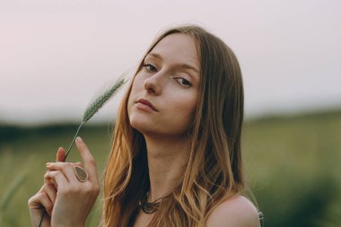 Gün batımında, uzun sarı saçlı, çok güzel, genç bir kadın. Sağlıklı yaşam tarzı kavramı. Gürültülü görüntü, film tahılı