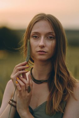 Günbatımı arka planında uzun sarı saçlı muhteşem genç bir kadın portresi. Sağlıklı yaşam tarzı kavramı. Gürültülü görüntü, film tahılı