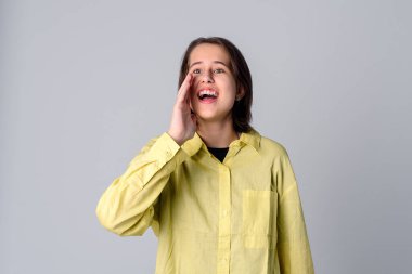 Sesinin duyulmasını istiyor. Açık ağzının yanında el ele tutuşan genç ve güzel bir kadın gizlice dedikodu yapıyor. Stüdyo çekimi, gri arkaplan