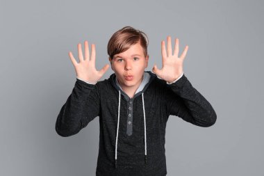 Şok olmuş komik bir çocuğun portresi. Genç çocuk kollarını kaldırdı. Beklenmedik haberler karşısında şaşkın şaşkın baktı, tamamen güvensizliğini gösterdi.