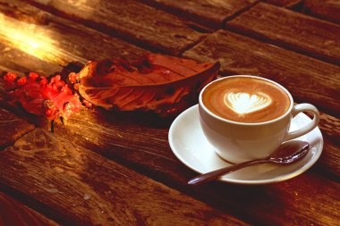 Ahşap masa ve kırmızı yaprakları latte veya cappuccino kahve