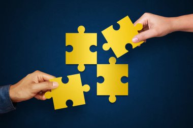 Eller bulmaca parçalarını mavi arka planda birleştiriyor. Takım kavramı, zafer ve takım çalışması