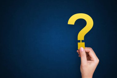 İşadamı mavi arkaplanda soru işareti tutuyor