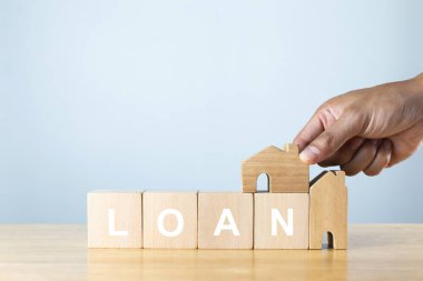 Bir ev modelini ve ahşap masanın üzerinde alfabe kredisiyle tahta küpleri tut. Konut kredisi yatırım kavramı