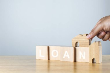 Bir ev modelini ve ahşap masanın üzerinde alfabe kredisiyle tahta küpleri tut. Konut kredisi yatırım kavramı