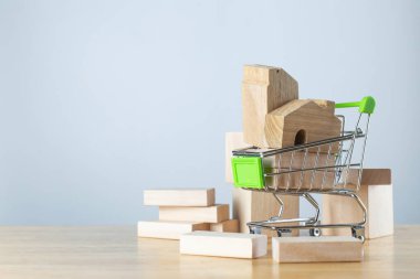 Minyatür ahşap ev modeli mini alışveriş arabasında ve tahtadan tahtalar ve konut yatırımları için. Konut kredisi ve emlak yatırımı kavramı