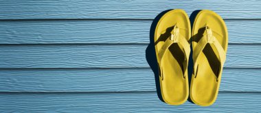 Parmak arası terlikler mavi arkaplanda izole edilmiş. Üst görünüm ve boşluk kopyala. Terlikler sarı