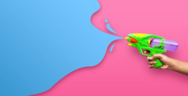Pembe arka planda plastik su tabancası var.