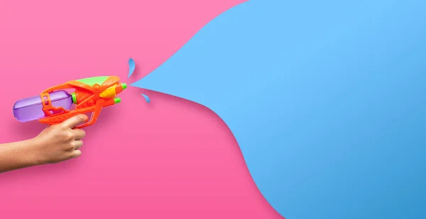 Pembe arka planda plastik su tabancası var.