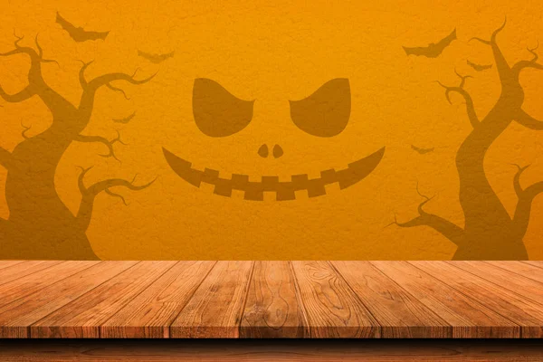 オレンジの壁の背景に影怖い顔を持つ木製の古いテーブル 前景のテーブル上にフォーカスした製品配置またはモンタージュの場合 ハロウィンカボチャと装飾のコンセプト — ストック写真