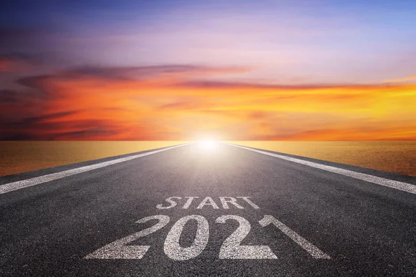 Asphalt yolu üzerinde ok kılavuzu ve 2021 harfli ve yüzeyinde START harfleri var. Gelecekteki amaçlar ve zaman geçirmek için başarı kavramı. Mutlu yıllar.