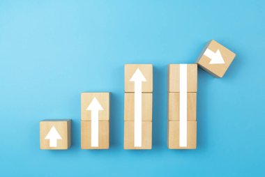 Yukarıyı gösteren okları olan tahta bir küp ve ok mavi arka planın üzerine düşüyor. Yatırım riski yönetimi kavramı