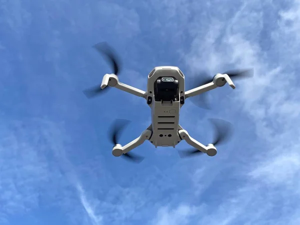 Flying white drone with camera. Unmanned aerial vehicle. Quadrocopter. Drone on blue sky background. Flying robot.