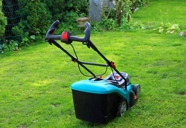 Lawn Mower. Lawn mower cutting green grass in backyard. Working lawn mower on green lawn with trimmed grass.