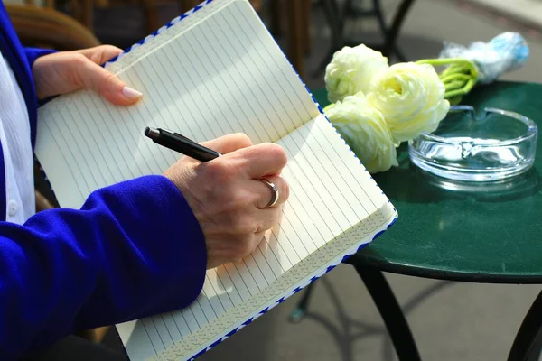 Businesswoman hands holding a notepad, writing while doing work at a coffee shop. Businesswoman hand working with finances.
