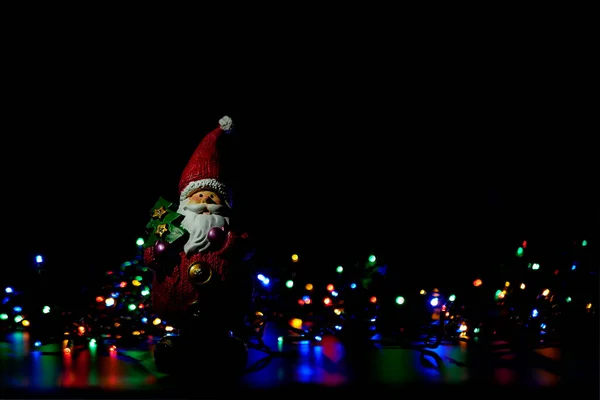 Figura Świętego Mikołaja Wśród Kolorowych Lampek Świątecznych Czarnym Tle — Zdjęcie stockowe