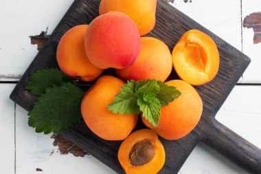 Ahşap zemin üzerinde nane yapraklı olgun sulu kayısılar. Boşluğu kopyala