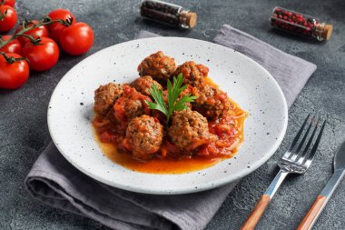 Tabakta domates sosuyla pişirilmiş köfte köftesi. Koyu beton arkaplan