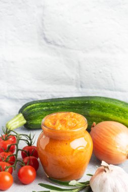 Kabak domatesinden ev yapımı havyar ve gri arka planda cam bir kavanozda soğan. Ev yapımı konserve, konserve sebze konservesi.
