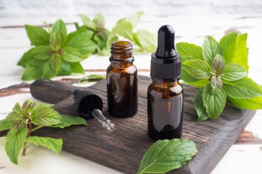 Koyu cam baloncuklardaki kokulu nane yağı, aromaterapi yağı kırsal ahşap arka planda doğal organik kozmetik.