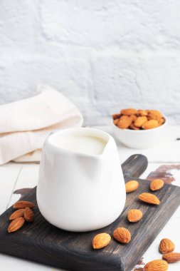 Gri arka planda seramik süt sürahisinde badem sütü. Boşluğu kopyala