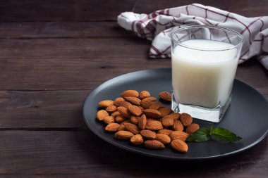 Cam bardaktaki badem sütü koyu ahşap arka planda. Boşluğu kopyala