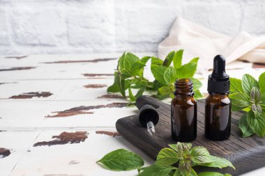 Koyu cam baloncuklardaki kokulu nane yağı, aromaterapi yağı kırsal ahşap arka planda doğal organik kozmetik.