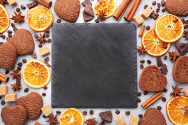 Çikolatalı kalp kurabiyeleri, portakallar tarçın ve baharatlar gri bir masada, üst manzara, boşluğu kopyala