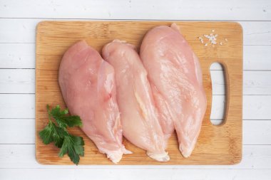 Çiğ tavuk göğsü fileto, kesme tahtasında çiğ tavuk eti. Beyaz arkaplan