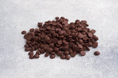 Çikolata damlaları gri beton zemine düşer. Tatlı süslemesi için çikolata parçaları..