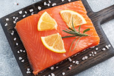 Somon fileto, ahşap doğrama tahtasında kırmızı tuzlu balık. Limon, biberiye baharatları