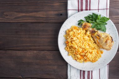 Lezzetli Asya pilavı, sebzeli pilav ve tabakta tavuk budu. Ahşap kırsal arkaplan Boşluk üst görünümünü kopyala