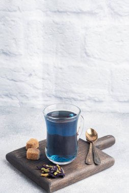 Thai blue tea anchan of buds klitoria Ternate in a glass cup, grey concrete background. Copy space