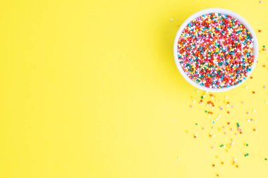 Şekerleme serpintileri, tabakta jöleli şeker, üst manzara. Boşluğu kopyala Sarı arkaplan.