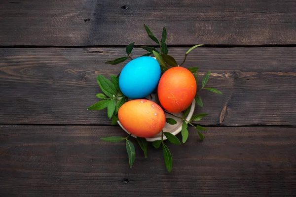 Easter eggs painted by hand colored on a dark wooden table, top view, copy space