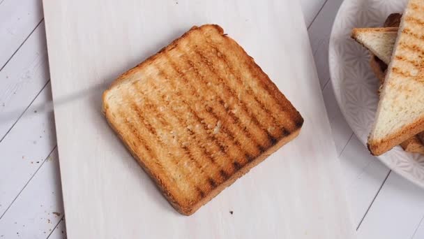Pâinea prăjită crocantă este tăiată pe o placă de tăiere pentru a face sandvișuri . — Videoclip de stoc