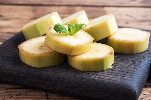 Banana and sliced banana into pieces with mint on wooden rustic background