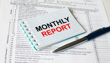 Finansal tablolarda elinde kalemle duran aylık yazılı not defteri. İş ve mali konsept